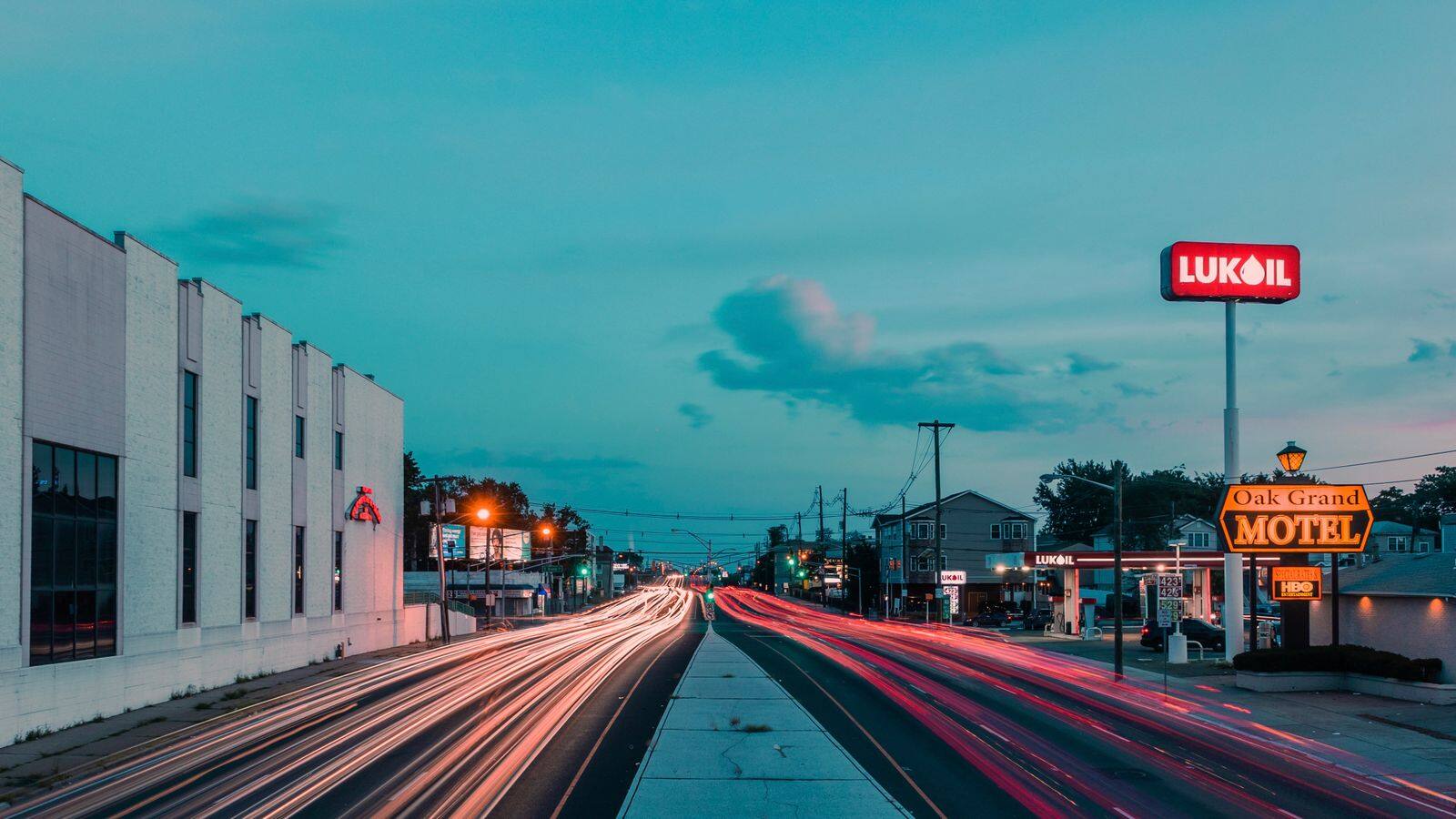 Evening traffic streaks past a commercial strip in Elizabeth