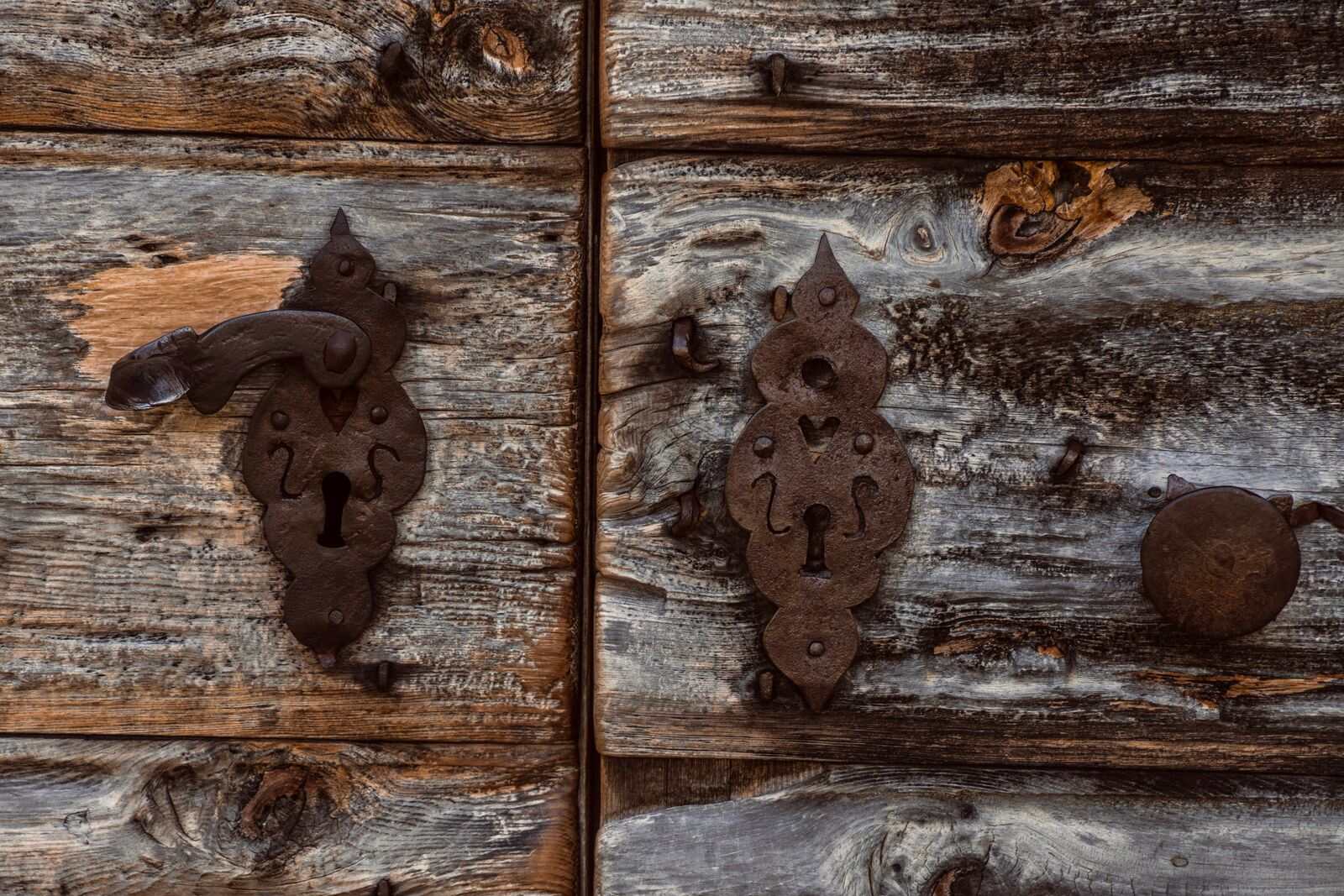 Antique iron keyhole plates on a weathered wooden door
