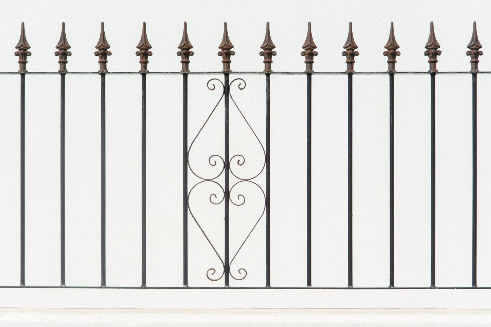 Pointed finials on an ornate wrought iron fence